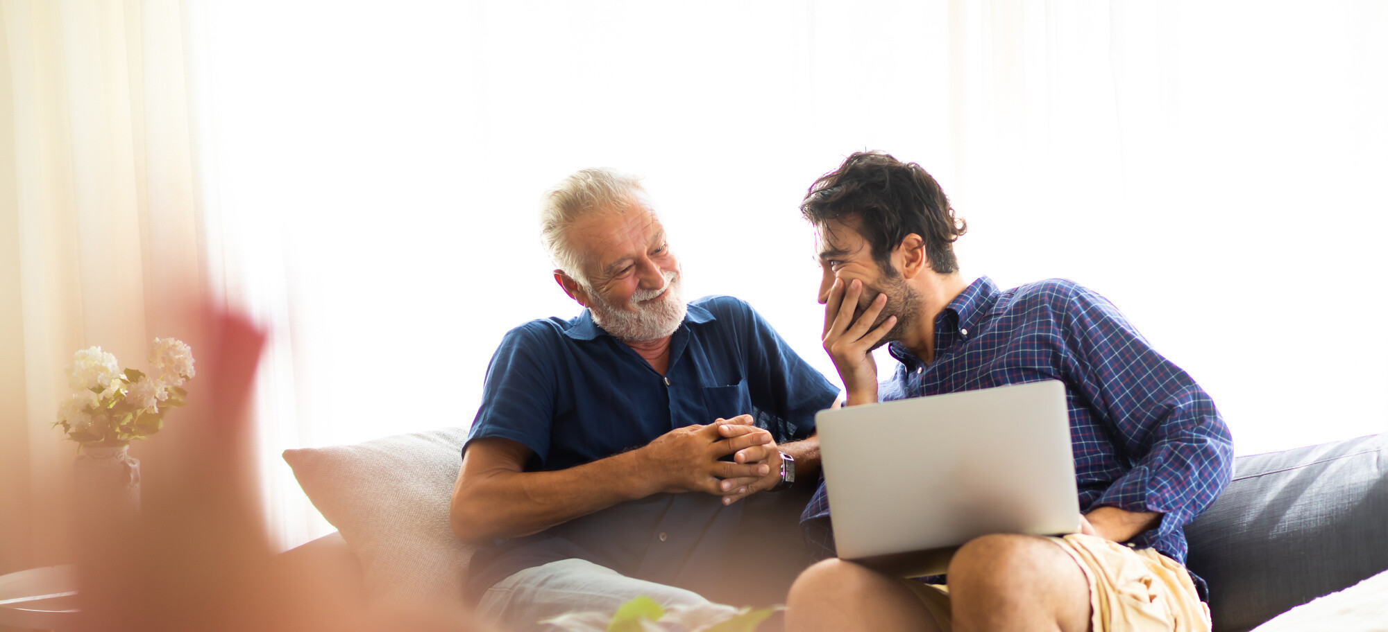 Lächelnder alter Vater und glücklicher Sohn, die mit Laptop auf Sofa sitzen | © Adobestock -	© navee